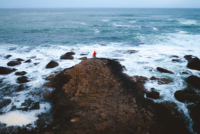 People standing on rock by sea against sky
