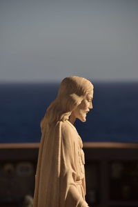 Side view of statue against sea against clear sky