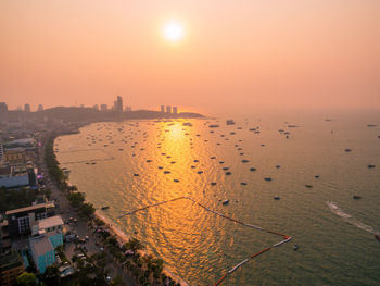 High angle view of buildings by sea against sky during sunset