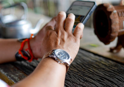 Close-up of person holding mobile phone on table