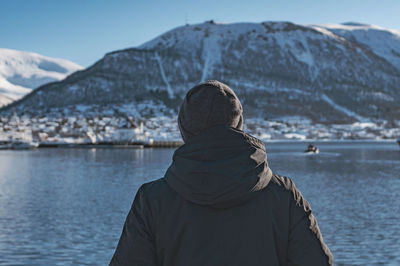 Rear view of person on snowcapped mountain by sea