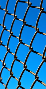 Low angle view of chainlink fence against blue sky