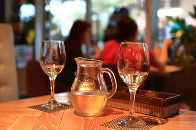 Wineglasses on table at restaurant with people sitting in background