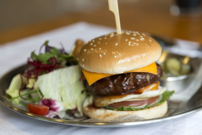 Close-up of hamburger with salad served in plate on table