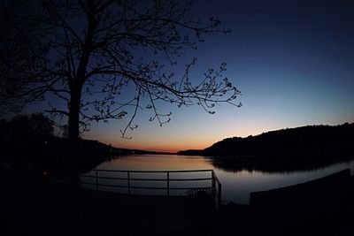 Reflection of silhouette trees in calm lake