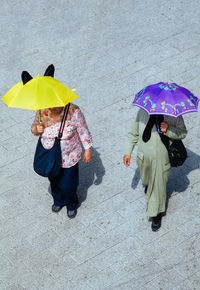 Women with umbrella walking on footpath
