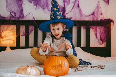 Cute little caucasian boy in a halloween costume with big orange pumpkin jack-o-lantern.