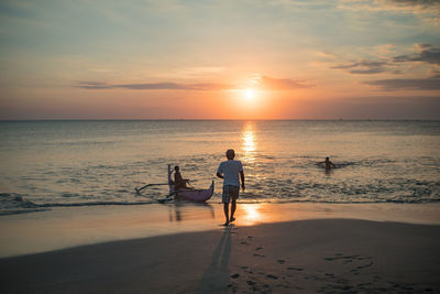 Silhouette people standing on beach against sky during sunset