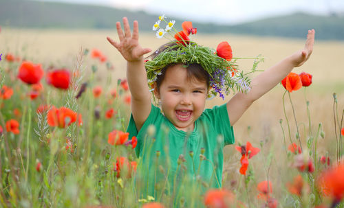 Portrait of happy girl with flowers on field