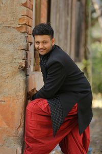 Portrait of young man standing against wall