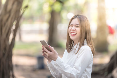 Happy businesswoman using mobile phone at park