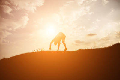 Silhouette woman on field against sky during sunset