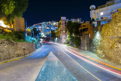 Light trails on road amidst buildings in city at night