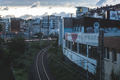 Railroad tracks by buildings in city against sky