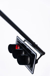 Detail of a traffic light with red light on. view of a black supporting structure against sky