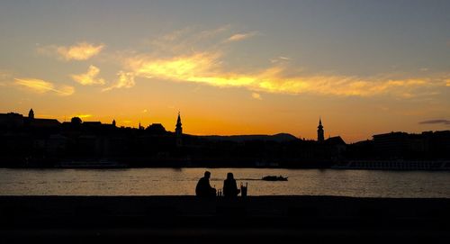 Silhouette people in river at sunset