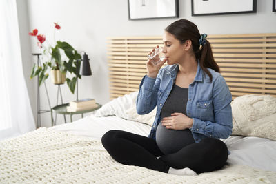 Pregnant woman drinking water at home