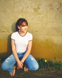 Thoughtful woman crouching against wall