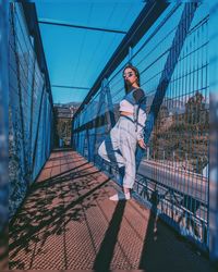 Full length portrait of young woman standing on footbridge