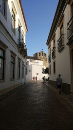 People walking on street in town against clear sky