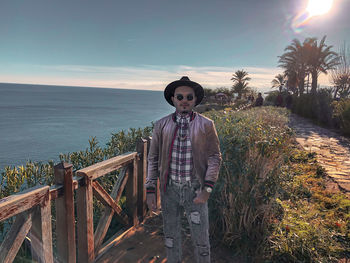 Portrait of young man standing by sea against sky