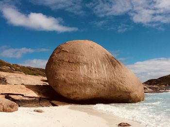 Rock formation on beach against sky