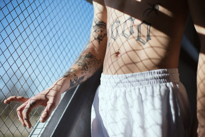 Midsection of woman wearing mask against fence