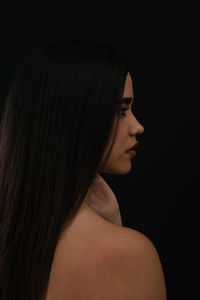 Portrait of face profile of young woman against black background