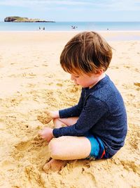 Rear view of boy sitting on shore at beach