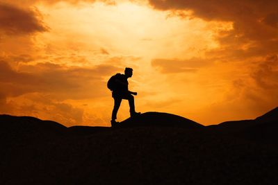 Silhouette man standing on mountain against sky during sunset