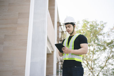 Full length of young man looking through mobile phone