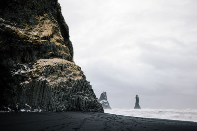 Rock formations on beach against sky