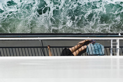 Low section of woman lying on boat at sea