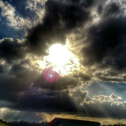 Low angle view of sun shining through clouds
