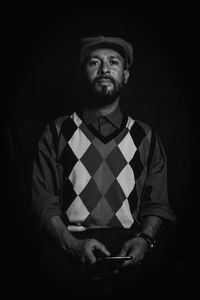 Young man using smart phone against black background