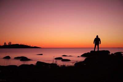 Silhouette man looking at sea against sky during sunset