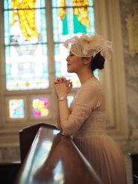 Side view of young woman praying in church