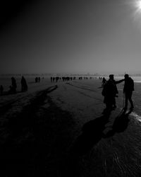 Silhouette people on beach against clear sky