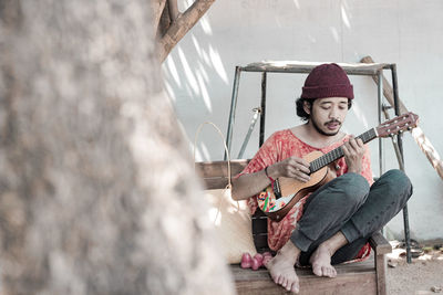 Man playing guitar while sitting outdoors