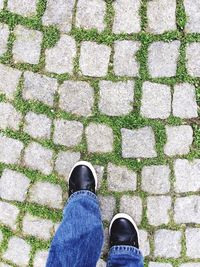 Low section of man standing on cobbled footpath