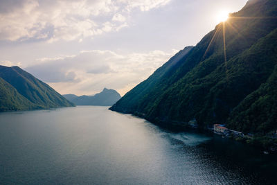 Scenic view of sea by mountains against sky during sunset