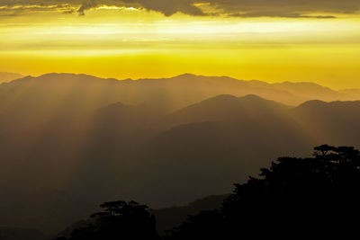 Scenic view of silhouette mountains against orange sky