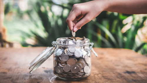 Close-up of hand holding glass jar on table