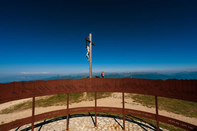 Man standing by railing against blue sky