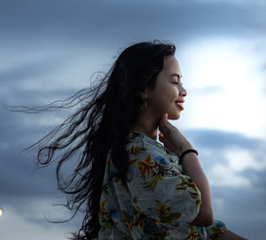 Young woman standing against sky