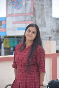 Portrait of young woman standing against wall