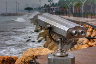 Close-up of coin-operated binoculars by sea