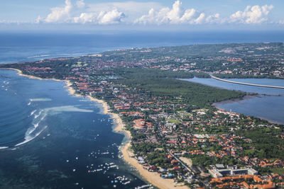 Aerial view of city by sea against sky