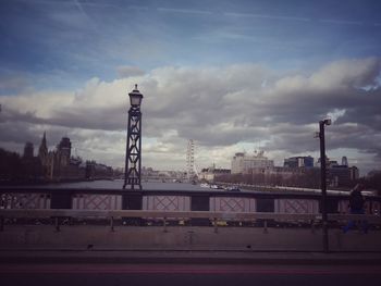 View of bridge and buildings against cloudy sky