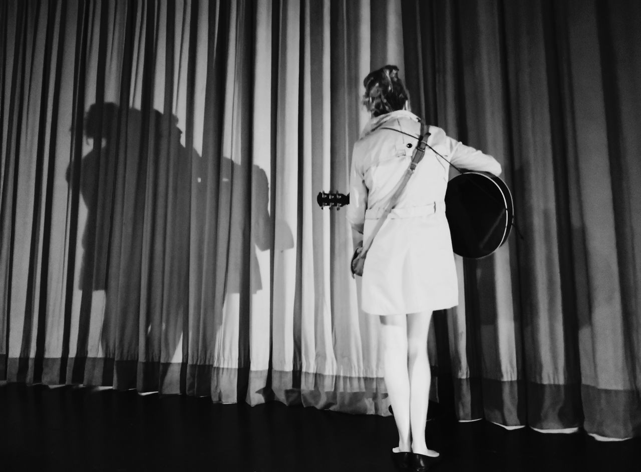 WOMAN STANDING AGAINST CURTAIN